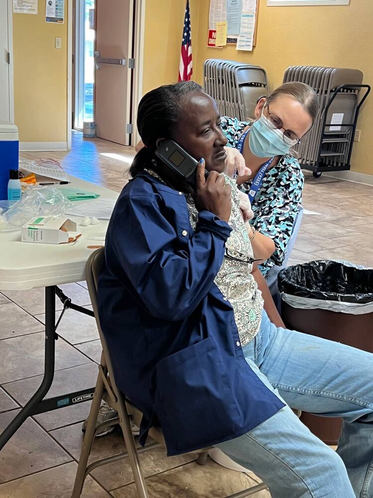 One man receiving Flu Vaccine shot in arm by a nurse while talking on the phone.